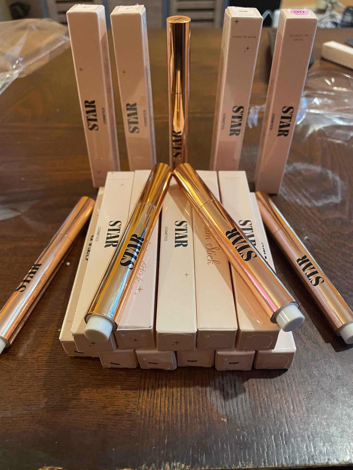 Boxes of Star click lip balms stacked and placed on a brown wooden table with golden lip balm lip gloss.