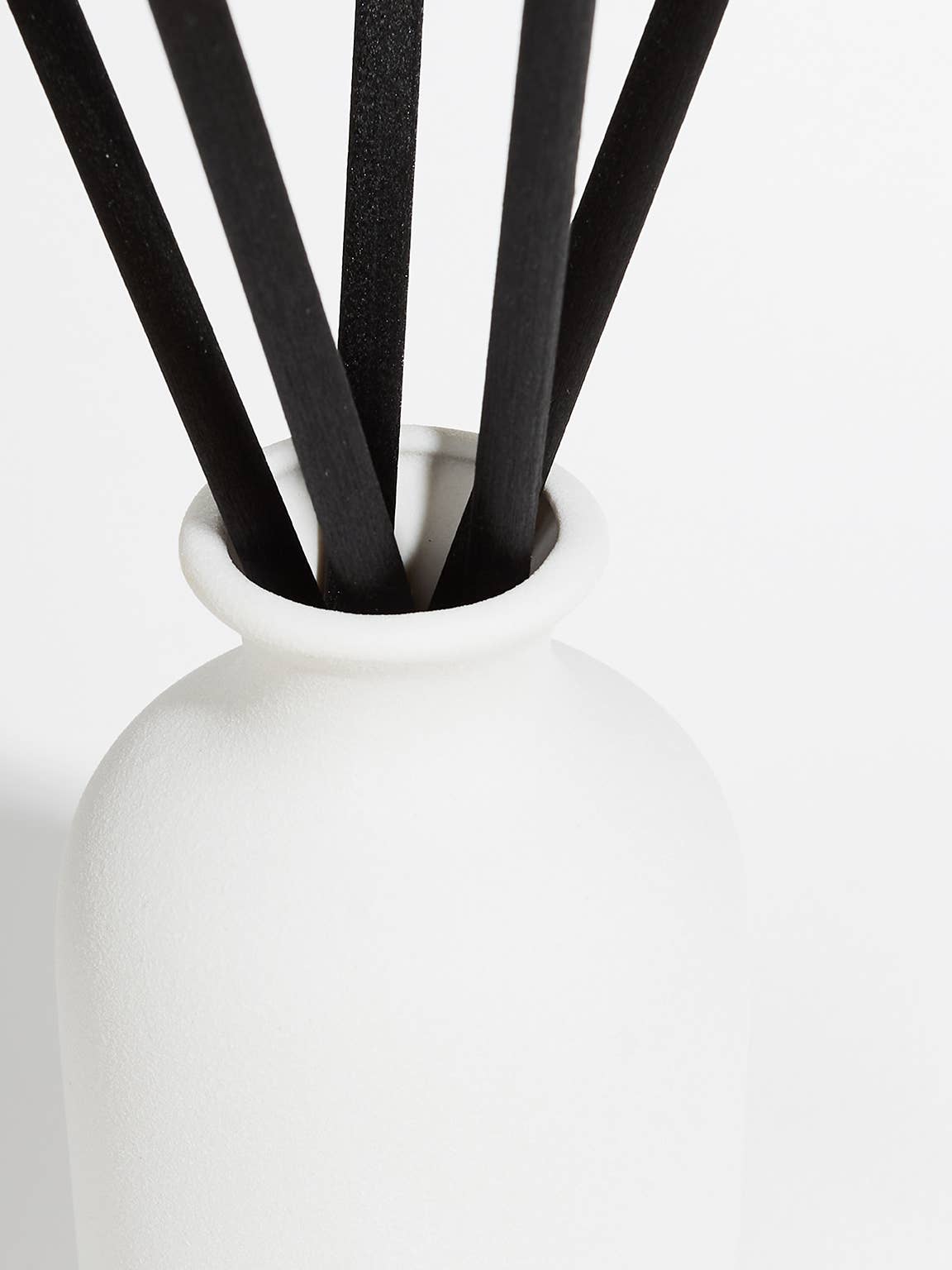 White vase with black sticks on a white background