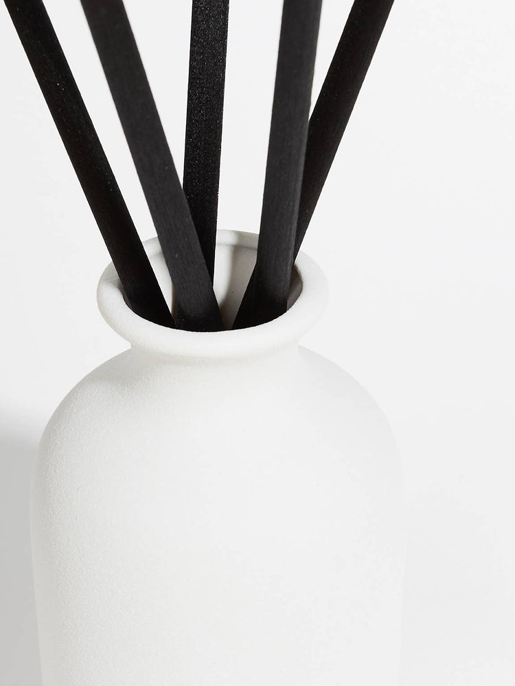White vase with black sticks on a white background