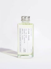 A clear glass bottle of Fresh Linen room spray with a silver metal cap, containing a pale yellow-green liquid, set against a plain white background.
