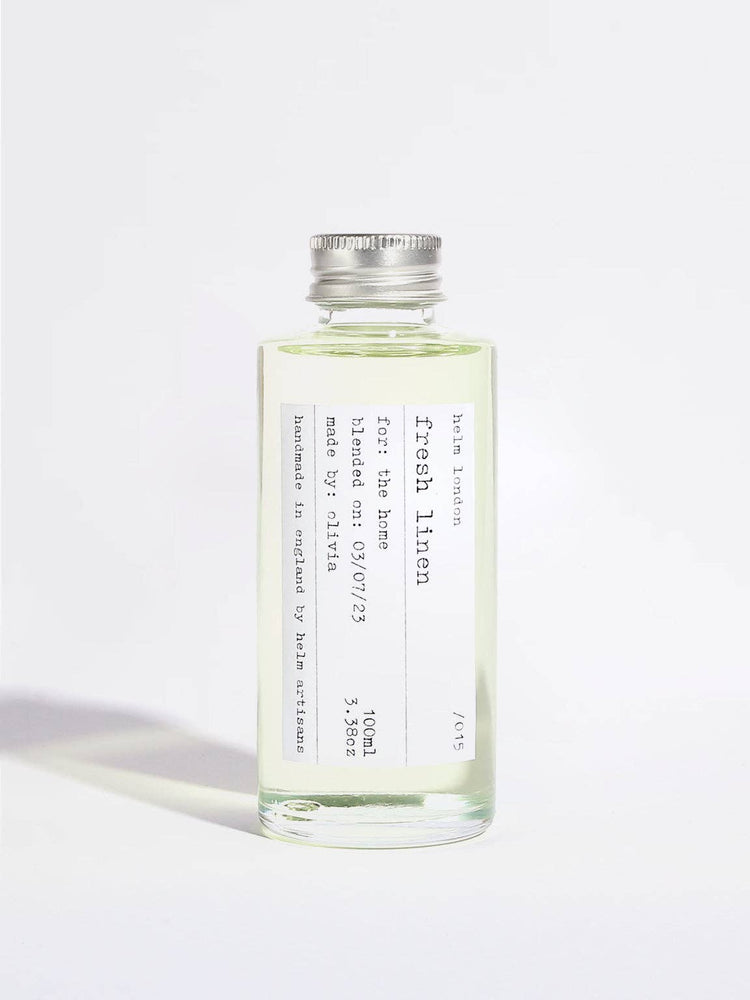 A clear glass bottle of Fresh Linen room spray with a silver metal cap, containing a pale yellow-green liquid, set against a plain white background.