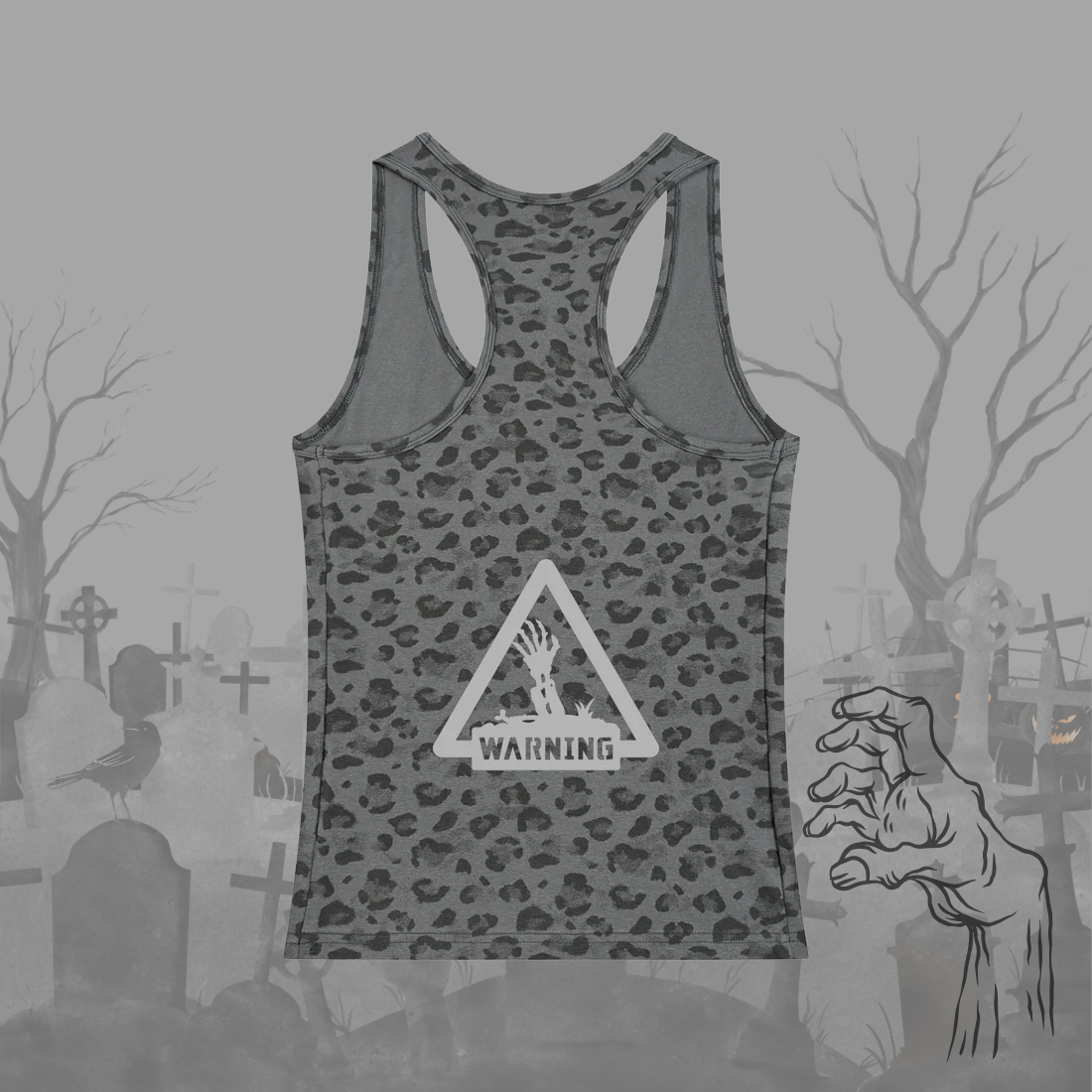 A gray racerback tank top with a dark gray leopard print pattern and a white warning sign graphic on the front, displayed against a spooky graveyard background with a zombie hand illustration.