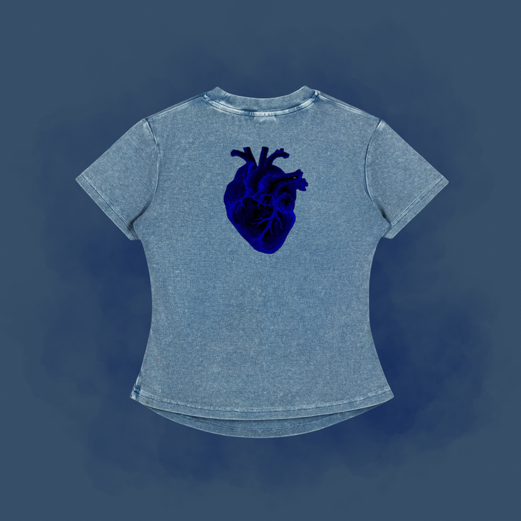 A light blue acid-wash t-shirt with a dark blue anatomical heart graphic on the back, displayed against a dark blue textured background.