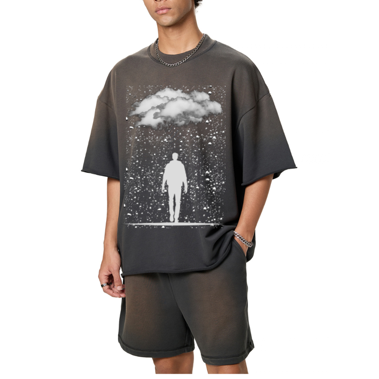 A man wearing a dark grey sun fade raw edge t-shirt, with raindrops on it and clouds and a silhouette of man walking. 