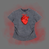 A short-sleeve t-shirt in a washed charcoal gray color, featuring a prominent red anatomical heart graphic on the chest. The t-shirt is displayed against a solid gray background with a red glow effect behind it.