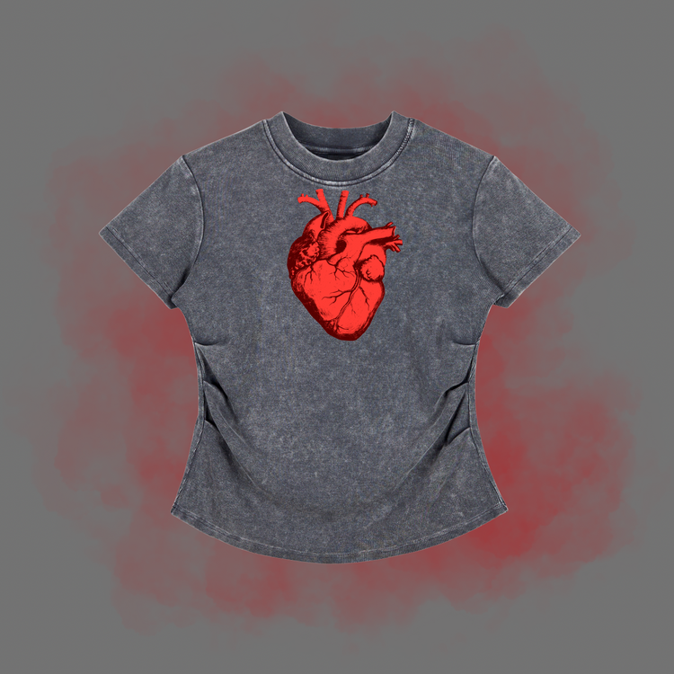 A short-sleeve t-shirt in a washed charcoal gray color, featuring a prominent red anatomical heart graphic on the chest. The t-shirt is displayed against a solid gray background with a red glow effect behind it.