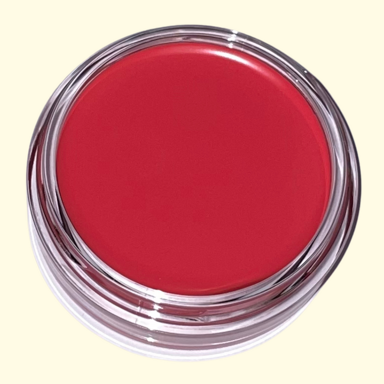Berry pink Red cosmetic cream blush in a clear container on a light yellow background