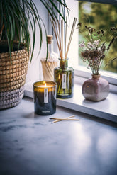 Candle with reed diffuser and decorative elements on a windowsill
