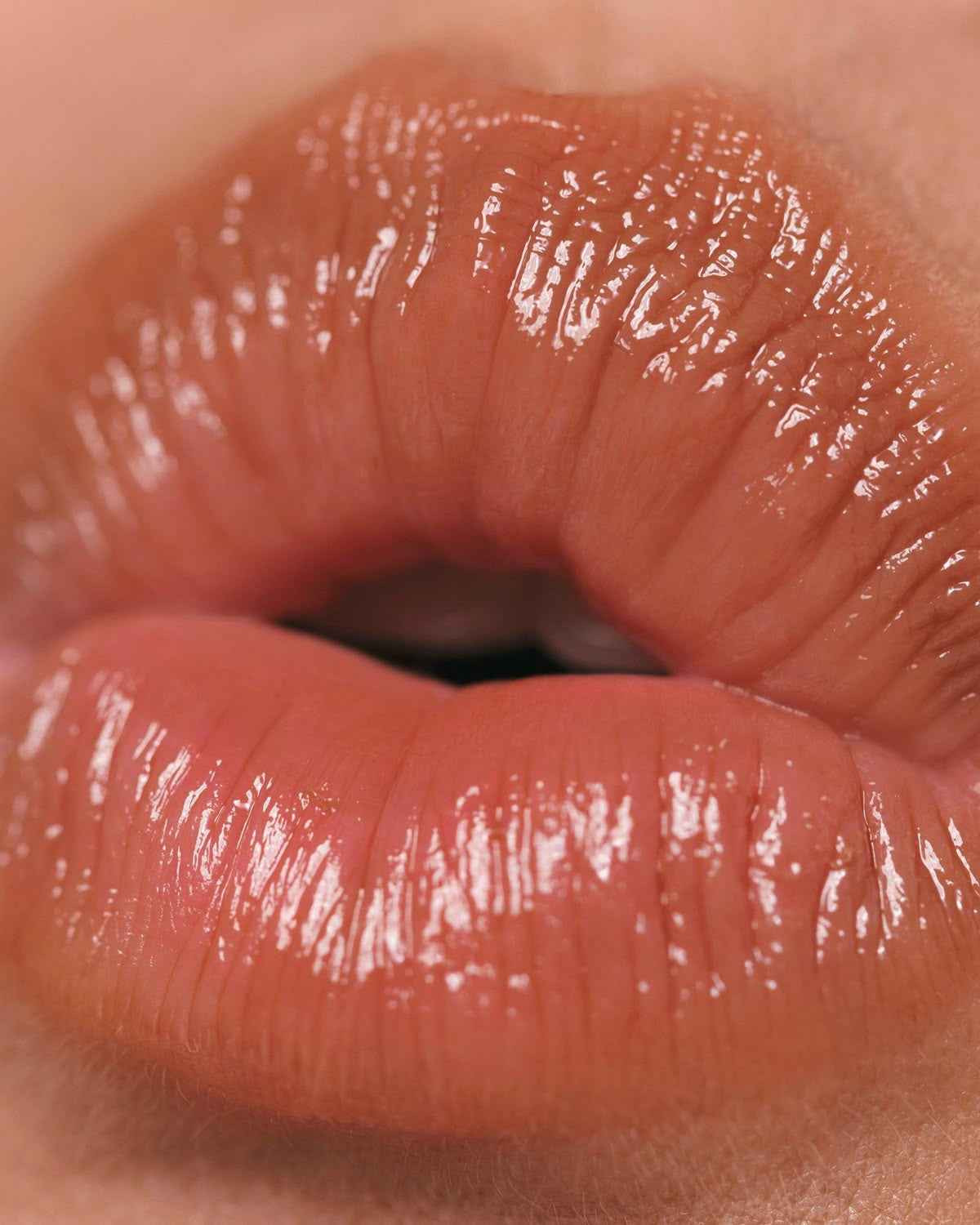 Close-up of glossy lips with a focus on texture and colour. A cream nude colour hydrated lip balm.