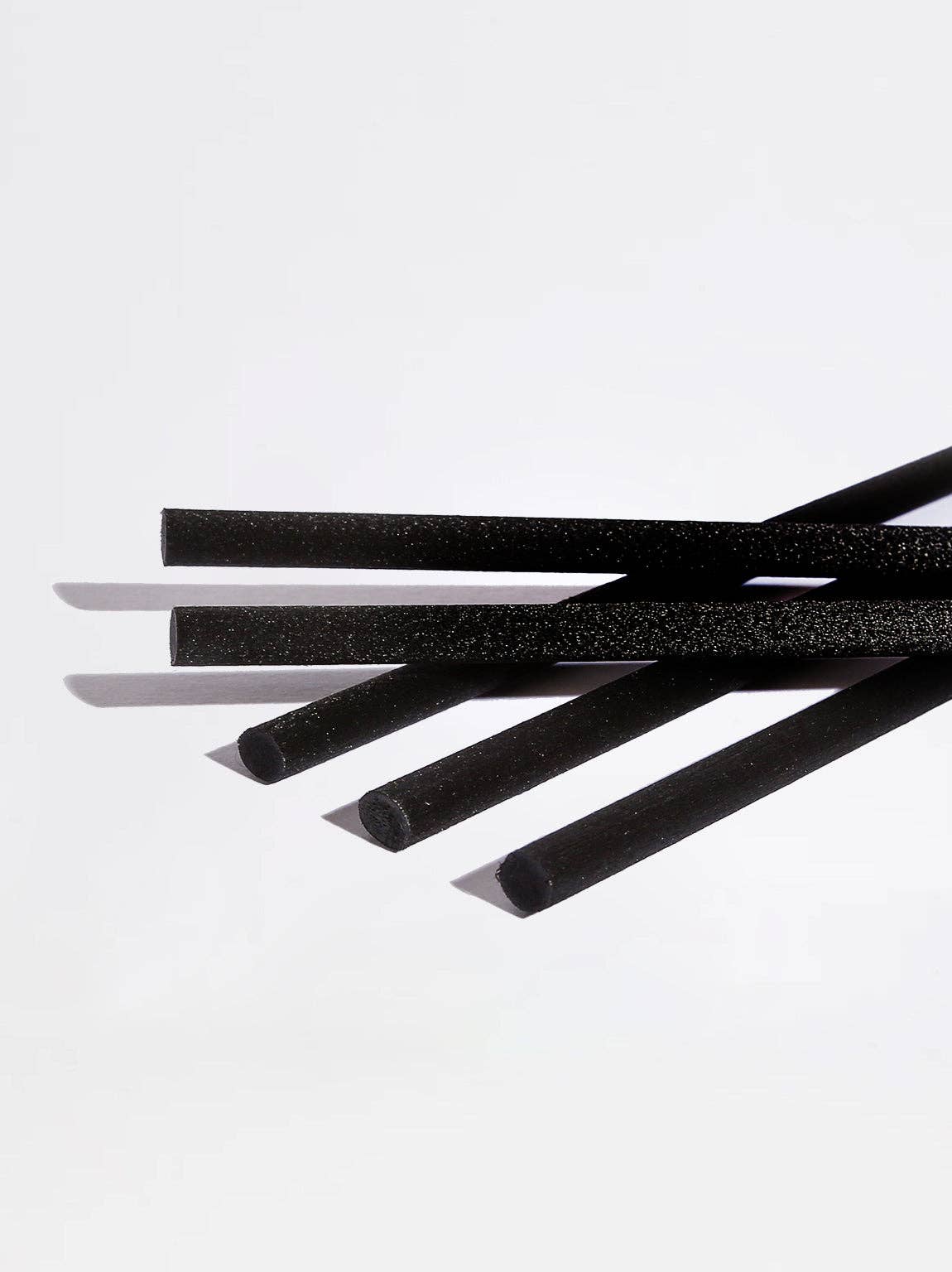 Five black foam straws with a textured surface, arranged diagonally on a clean white background.