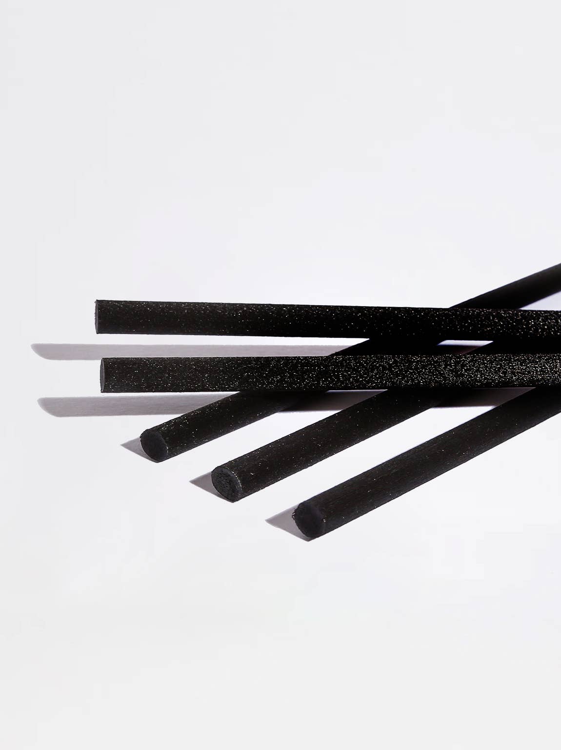 Five black foam straws with a textured surface, arranged diagonally on a clean white background.