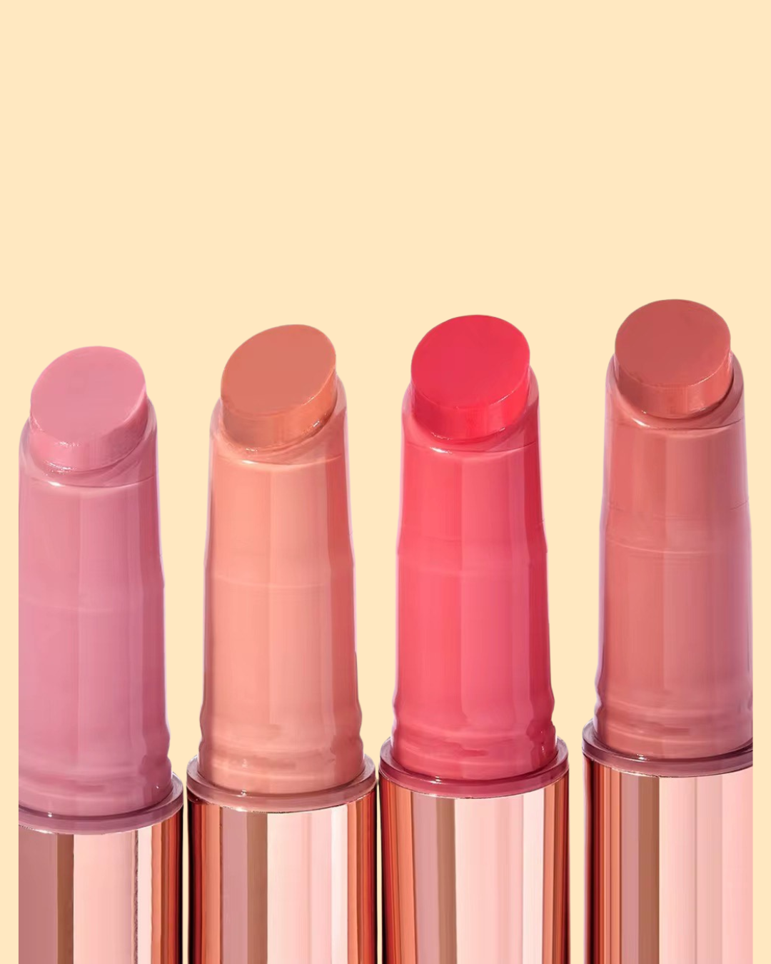 Four lip balm gloss with pink and red, light peach and berry pink shades on a beige background