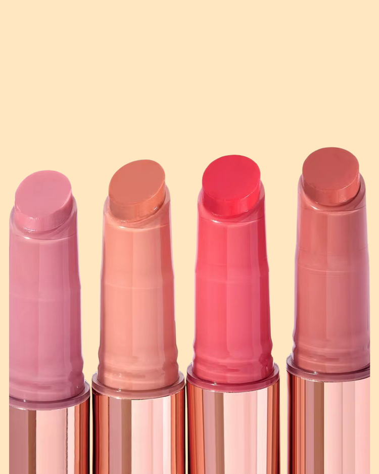 Four lip balm gloss with pink and red, light peach and berry pink shades on a beige background