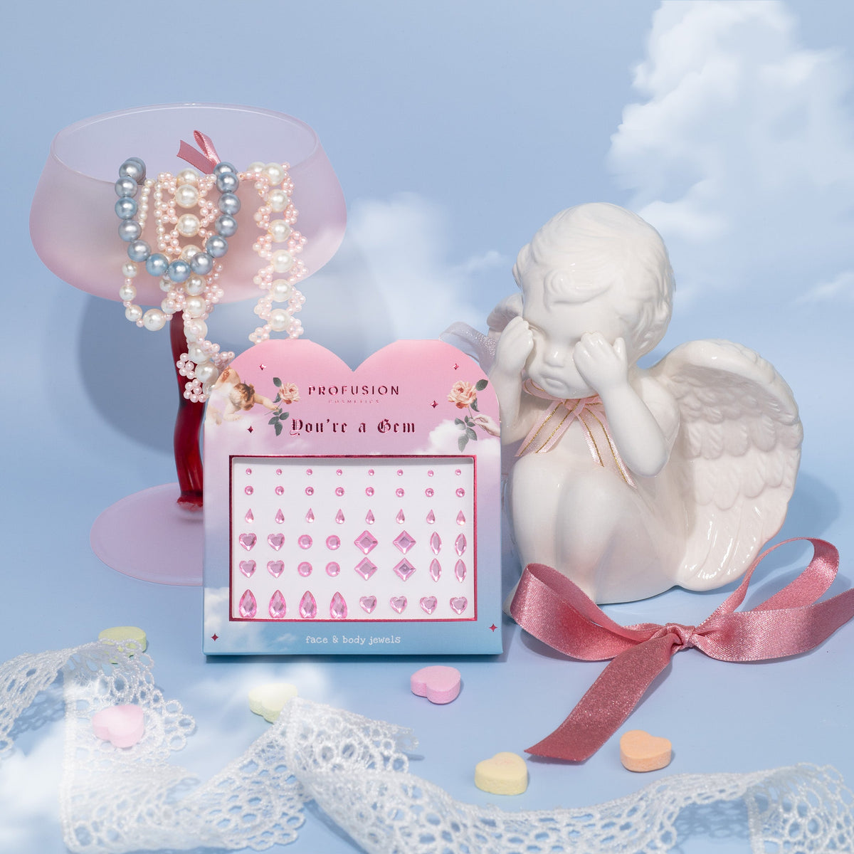 Gemstones in different shapes with angel figurine, pearls, and candy on a blue background
