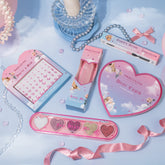 Gemstones in different sizes, eyeshadows palette in 5 shades (gold, silver, white, red) in the shape of a love heart and pearls in the background, ribbons, and love heart shaped pad