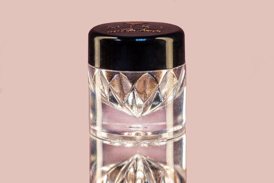 Makeup product with a metallic cap on a pink background
