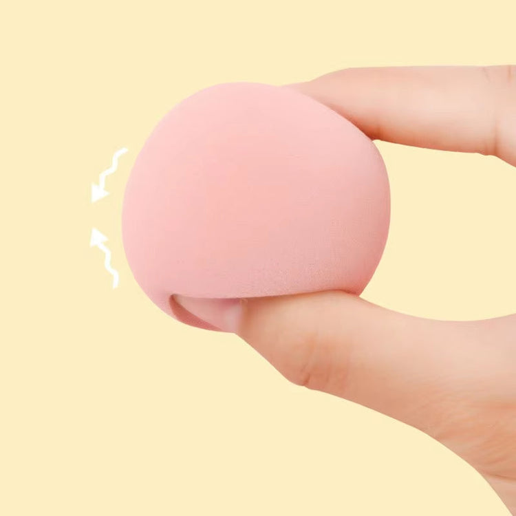 Pink sponge/beauty blender held between fingers against a yellow background 