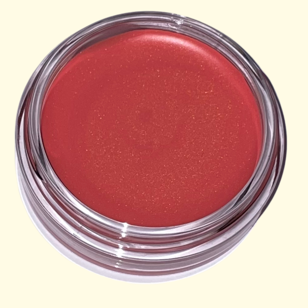 Red cosmetic cream blush in a clear container on a light yellow background