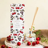 Reed diffuser with cherry design packaging on a wooden surface