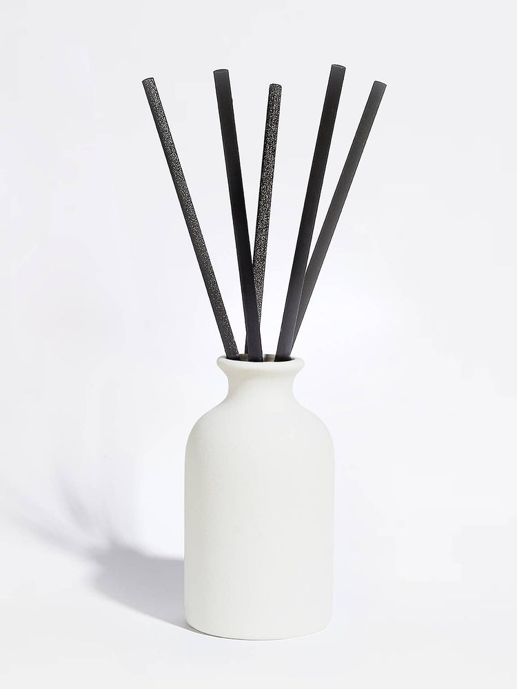White vase with black sticks on a white background