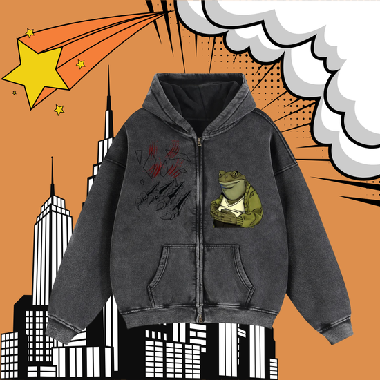 A dark gray zip-up hoodie with a frog graphic and red claw marks, displayed against a comic-book style background with an orange sky, white clouds, and black-and-white city buildings.